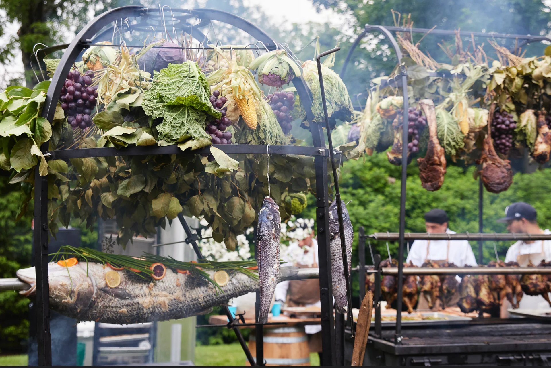 Grapes and vegetables hanging from a garden arbor at an outdoor market or vineyard event